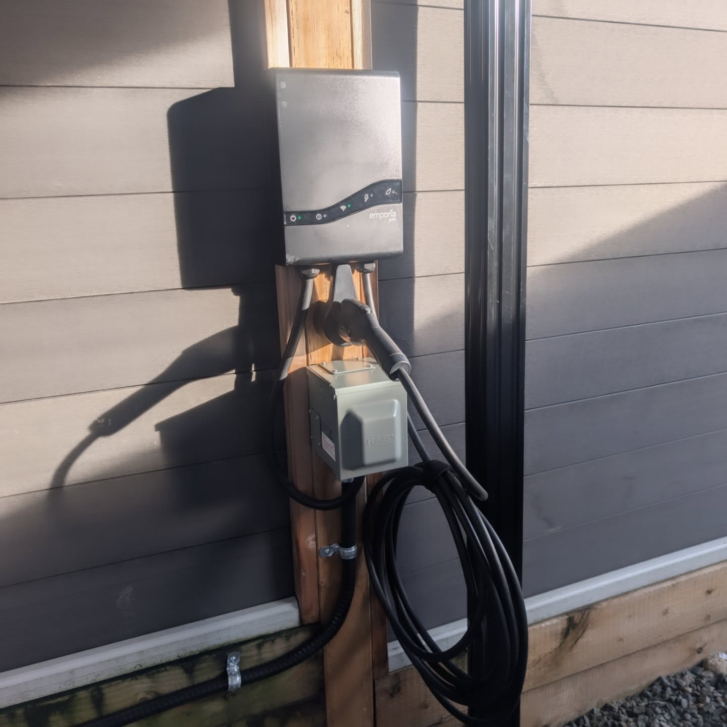 Emporia EV charger mounted on an exterior wall with charging cable