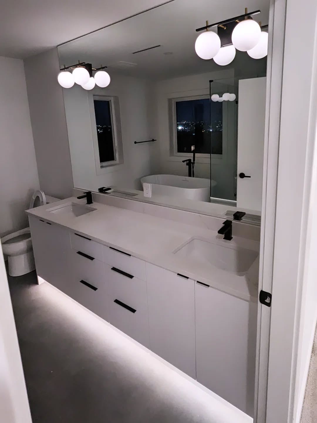 Double bathroom vanity with globe lights and accent lighting beneath the cabinets